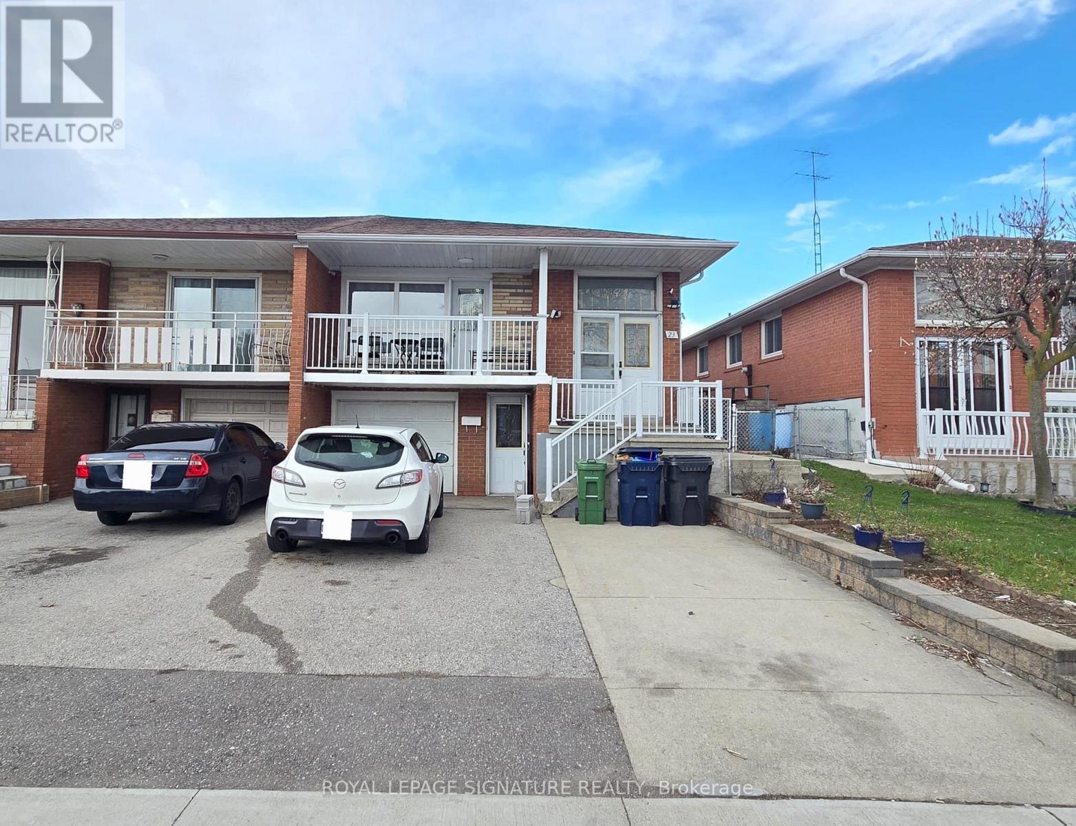 A car is parked in a driveway in front of a two-story building.