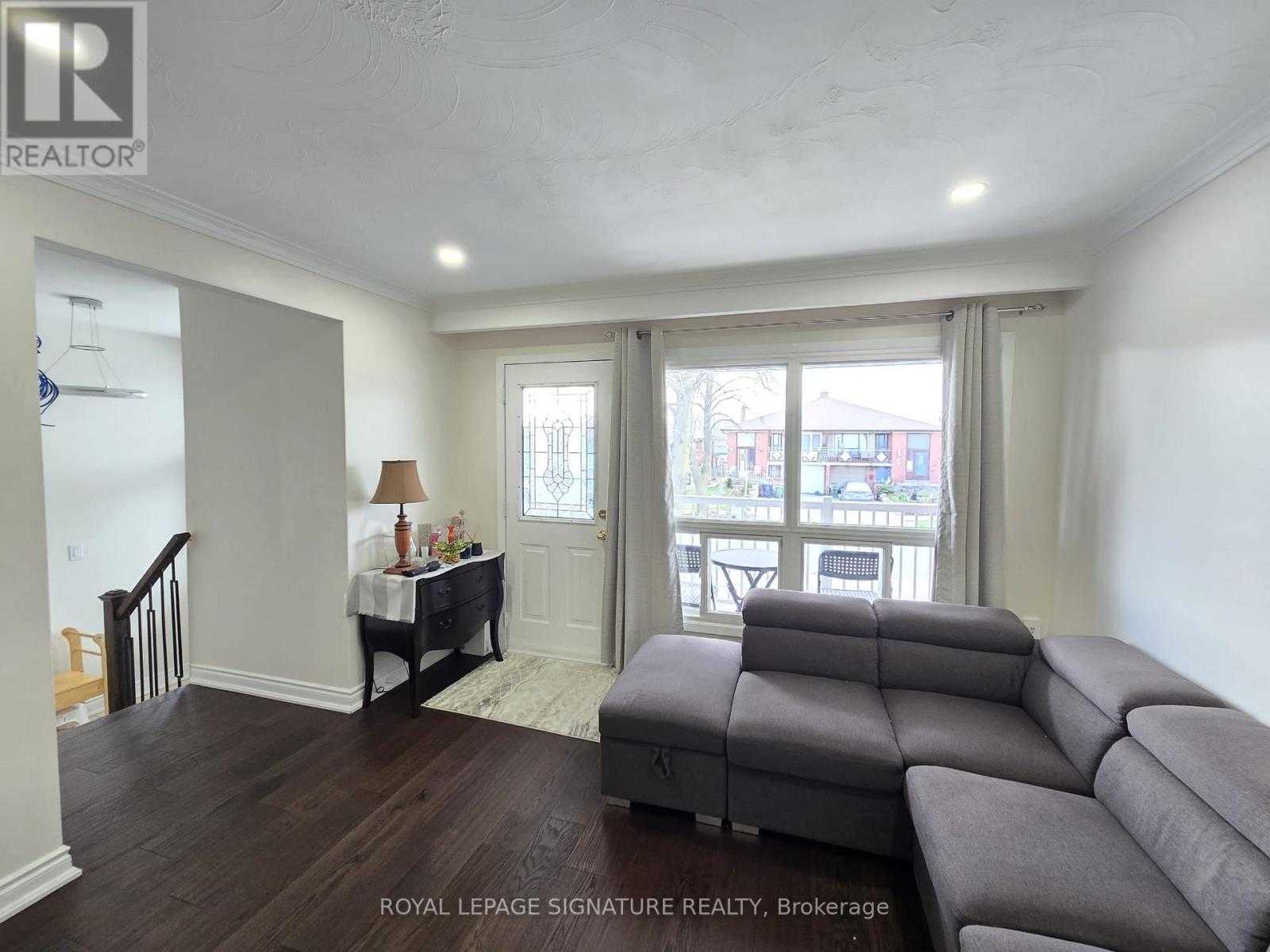 A living room with a grey couch and a table with a lamp.