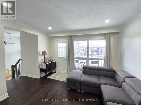 A living room with a grey couch and a table with a lamp.