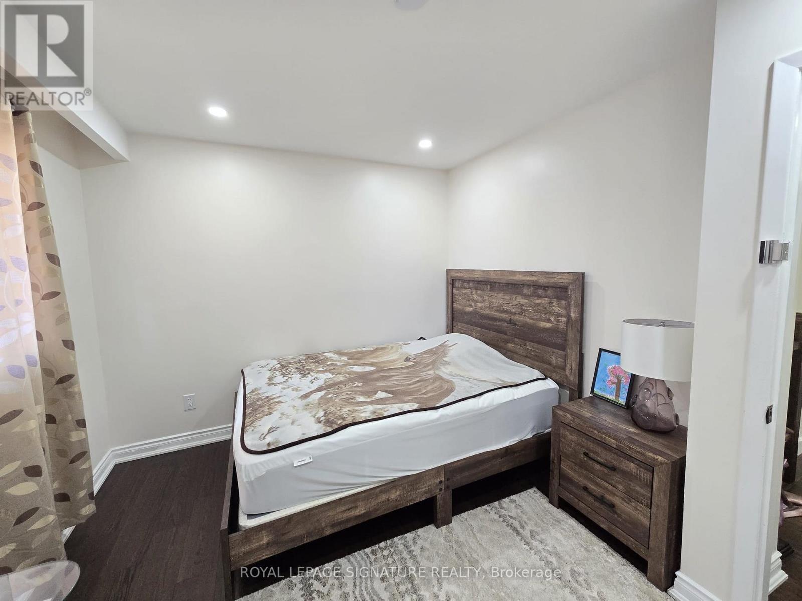 A bedroom with a bed, nightstand, and lamp.