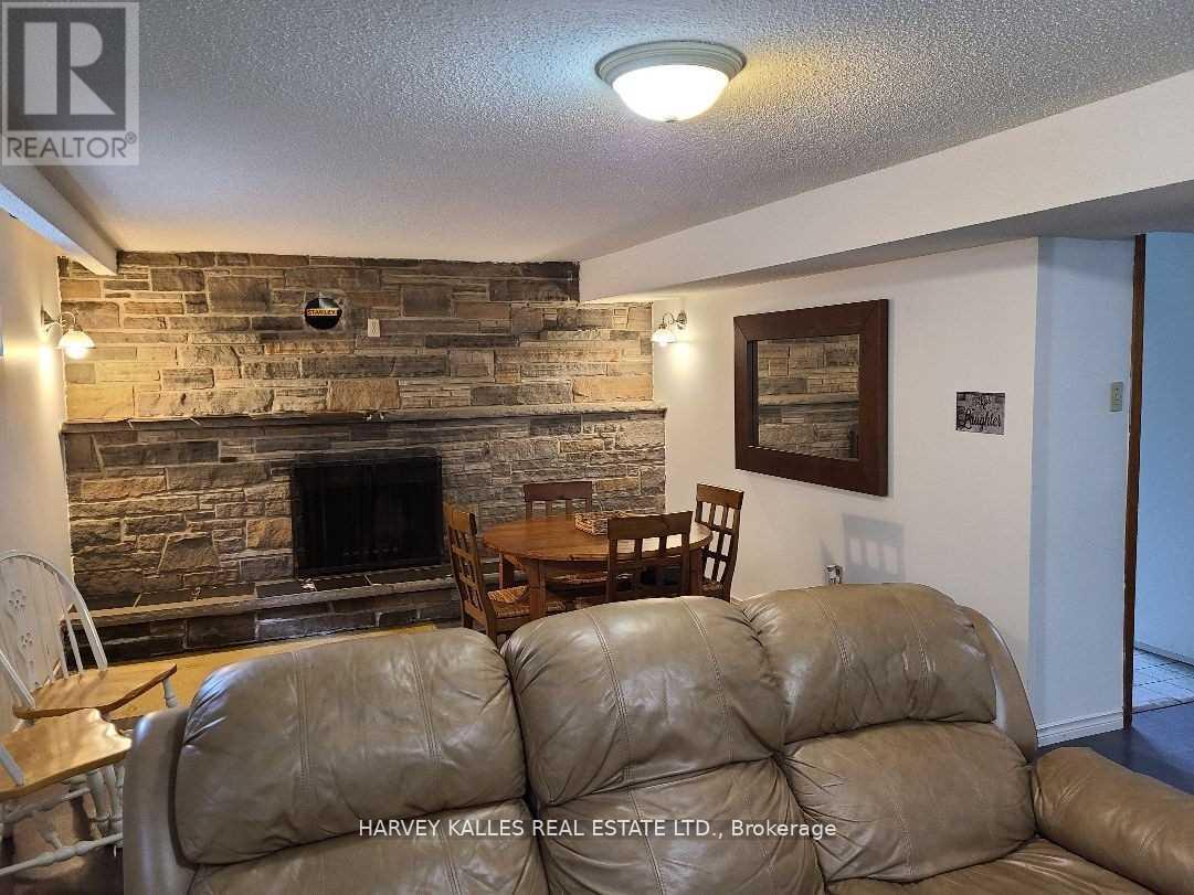 A living room with a stone fireplace and a brown leather couch.