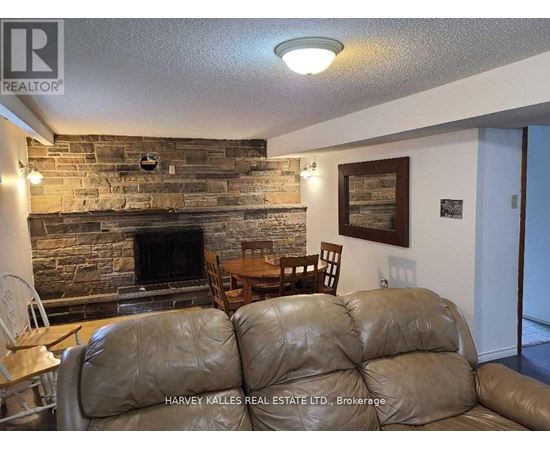 A living room with a stone fireplace and a brown leather couch.