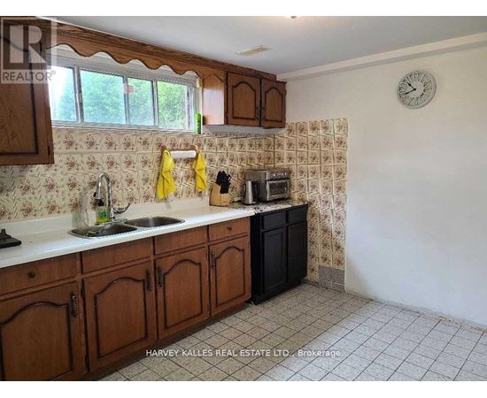A kitchen with wooden cabinets and a clock on the wall.