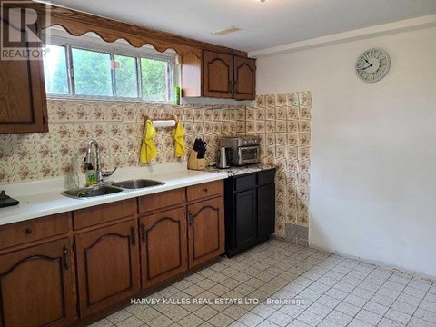 A kitchen with wooden cabinets and a clock on the wall.
