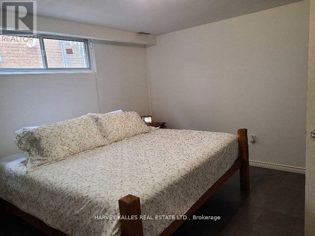 A bedroom with a bed, nightstand, and window.