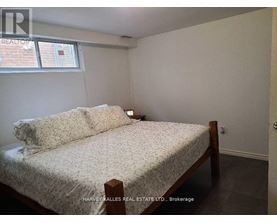 A bedroom with a bed, nightstand, and window.