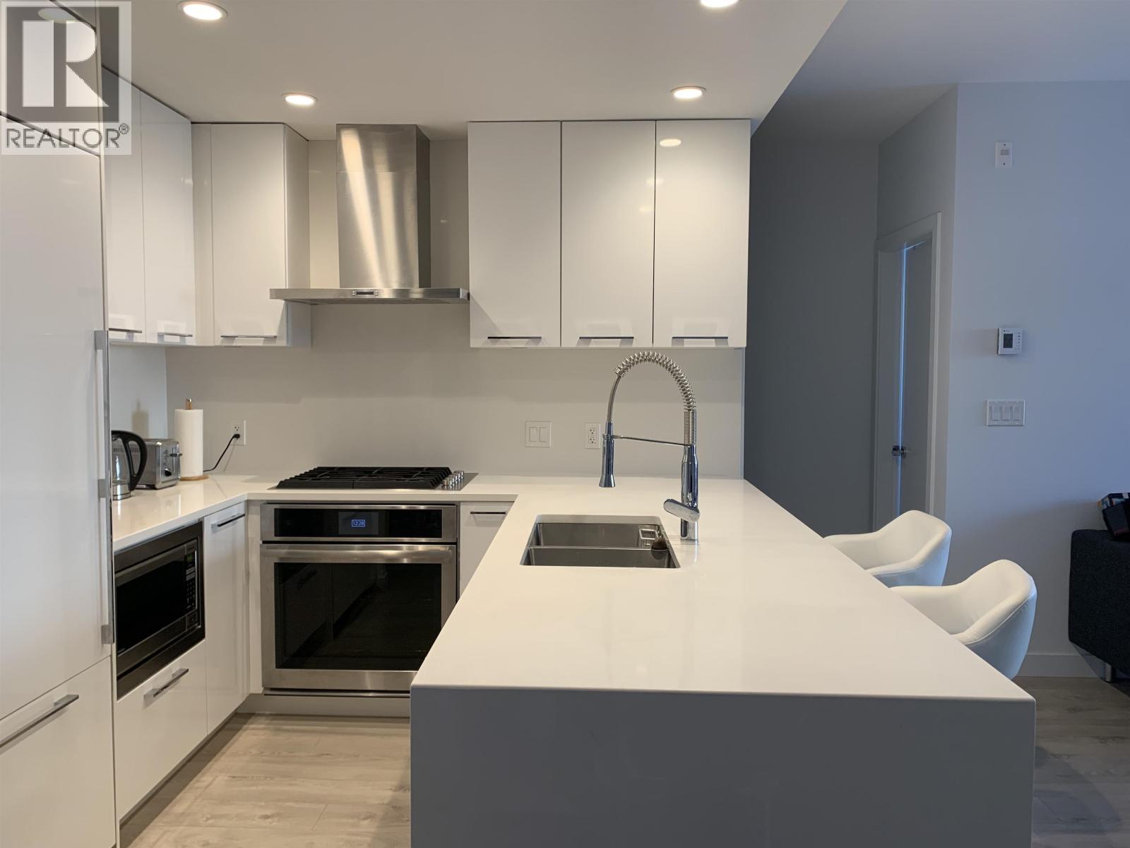 A modern kitchen with white cabinets and stainless steel appliances.