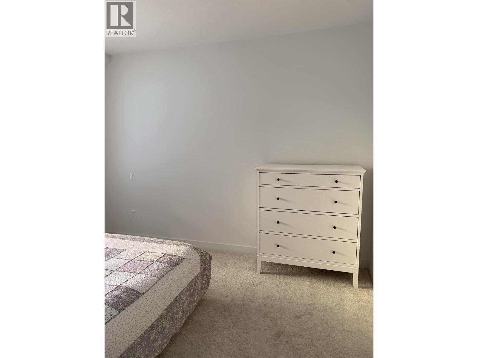 A bedroom with a bed and a dresser.