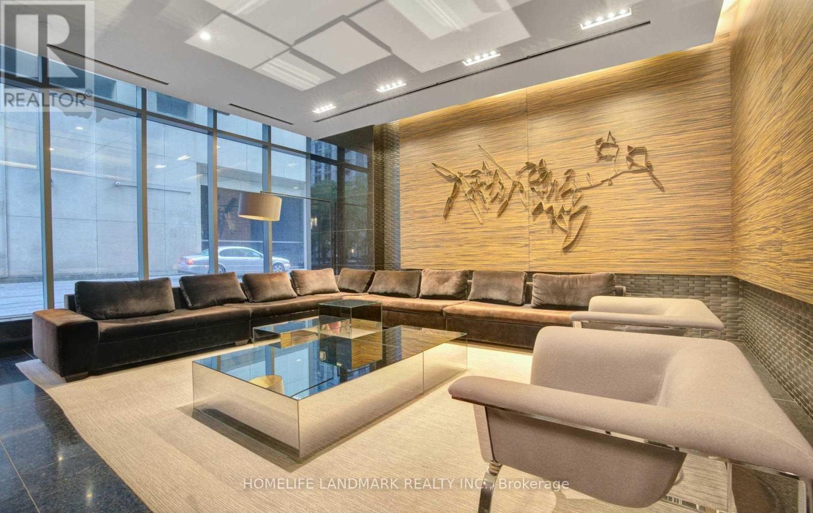 A modern living room with a glass table and a wooden wall.