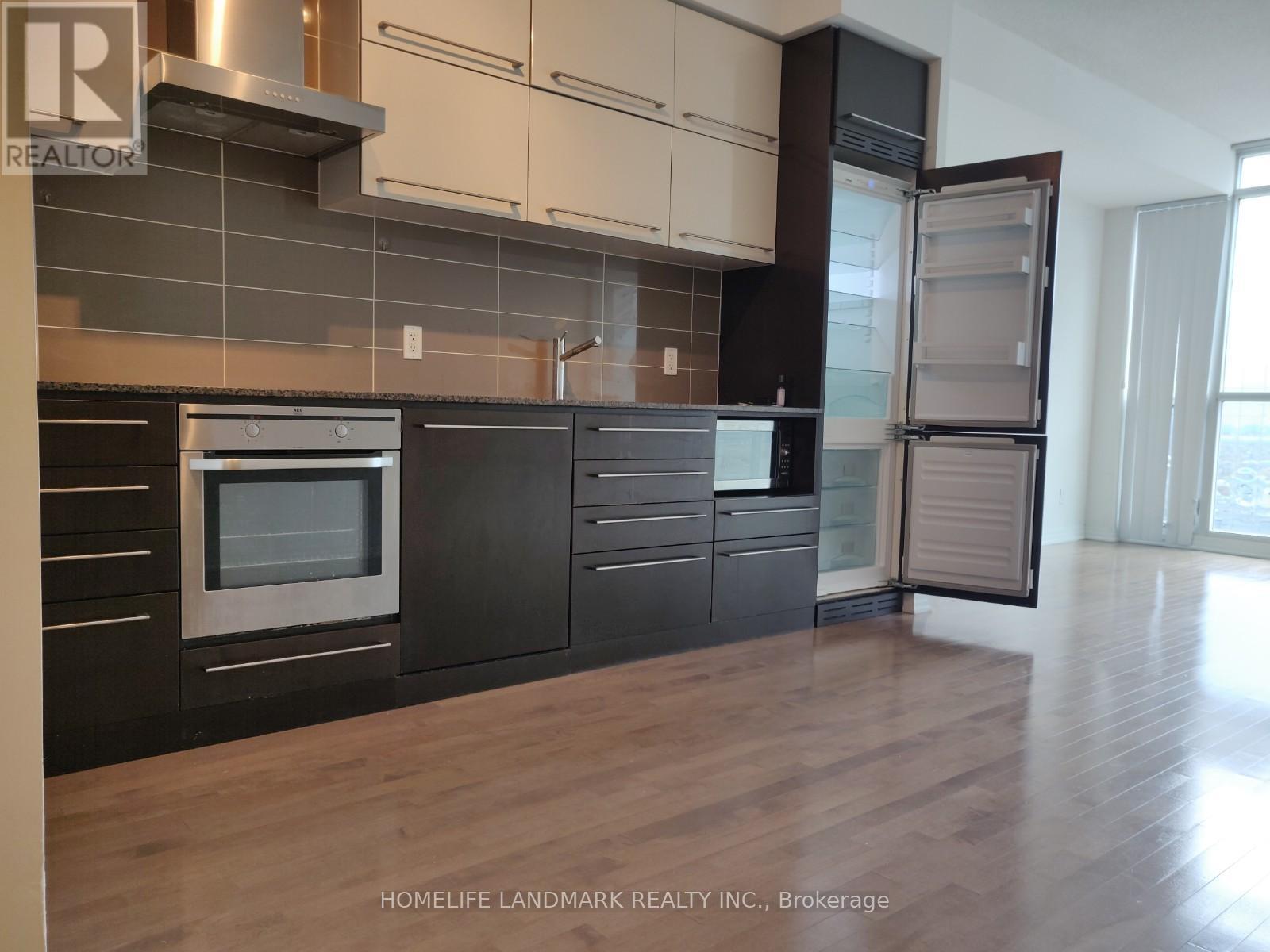 A modern kitchen with a stainless steel oven and black cabinets.