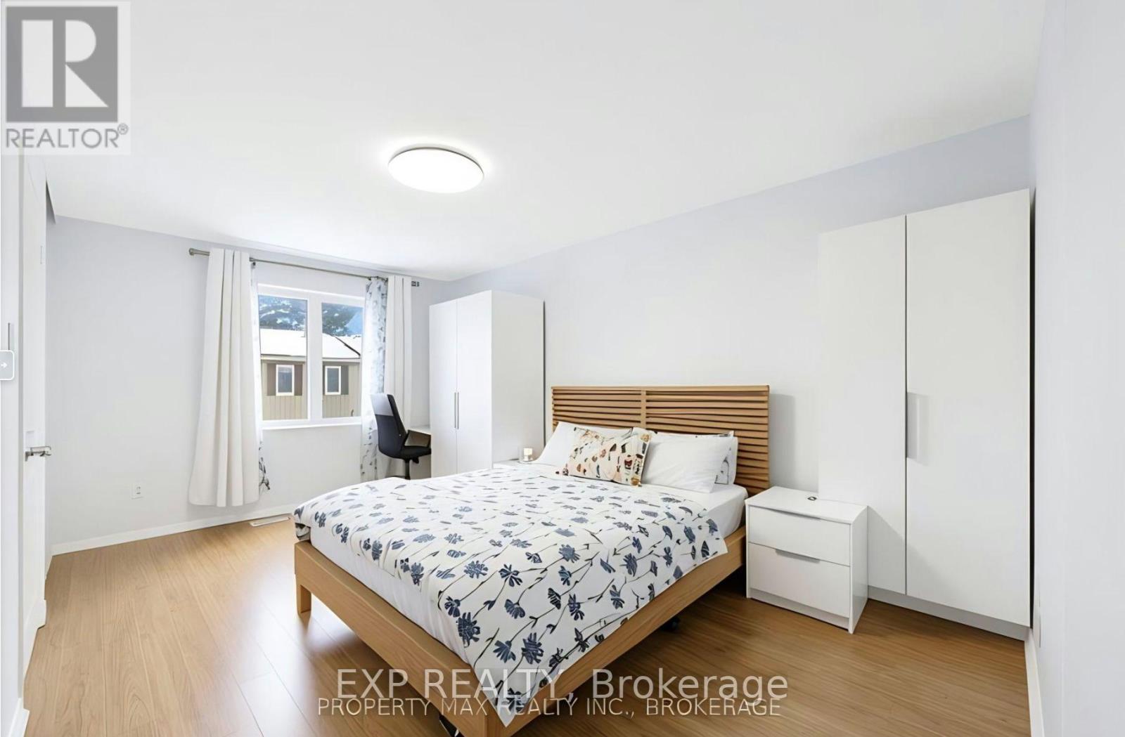 A bedroom with a bed, nightstand, and chair.