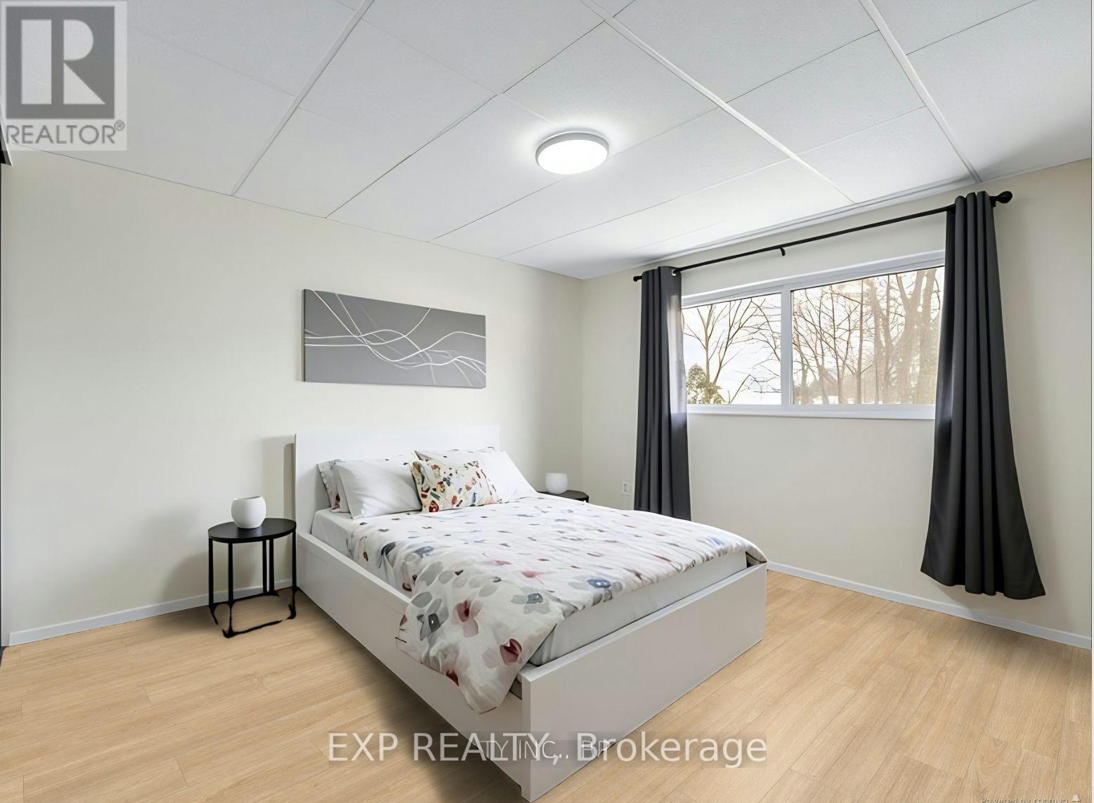 A bedroom with a bed, nightstand, and window.