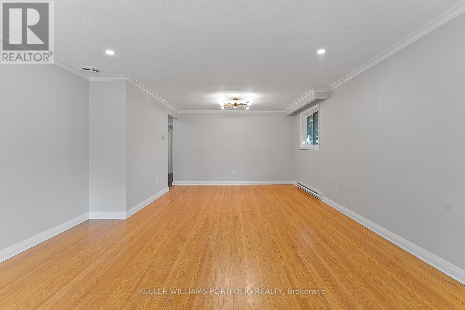 A spacious room with wooden flooring and white walls.