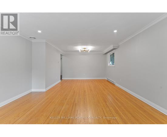 A spacious room with wooden flooring and white walls.