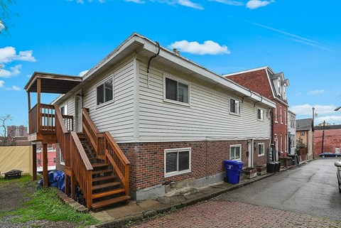A house with a red brick wall and a wooden staircase.