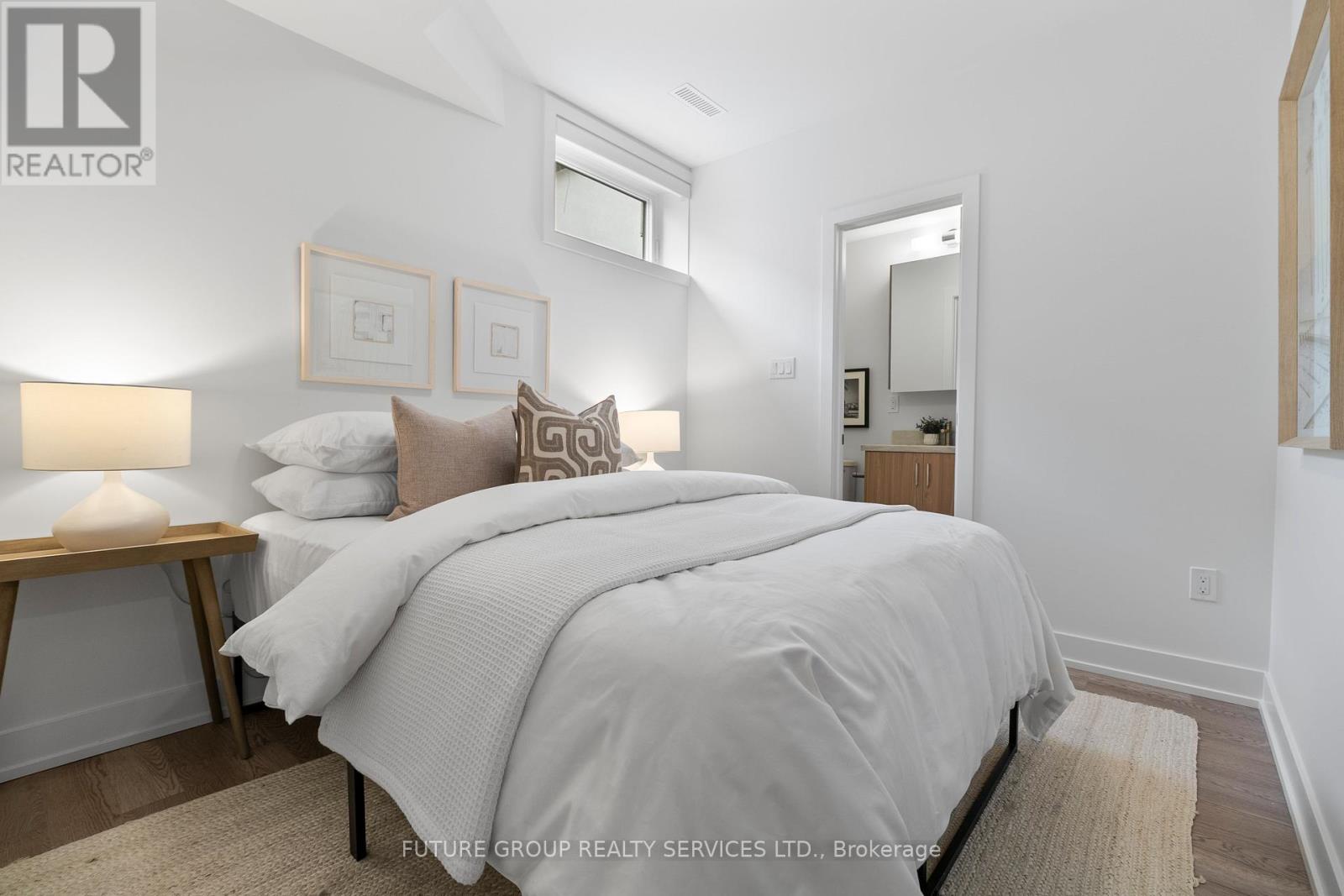 A bedroom with a large bed and a lamp on a side table.
