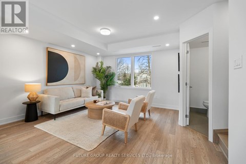 A well-lit, spacious living room with a large painting on the wall and a view of the outdoors through the window.