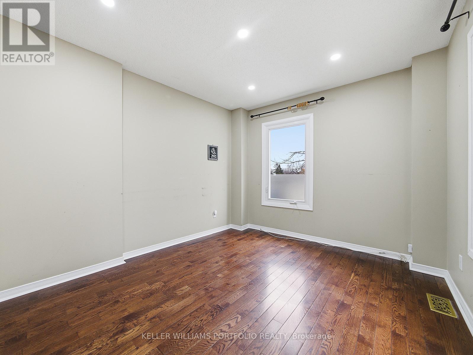 A spacious room with wooden flooring and a window.