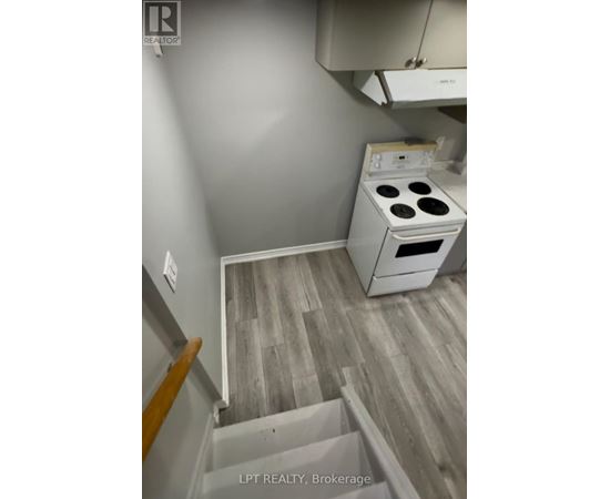 A small kitchen with a stove and a wooden floor.