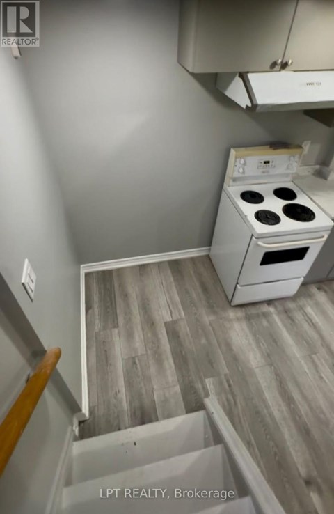 A small kitchen with a stove and a wooden floor.