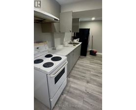 A white stove and oven in a kitchen with a black fridge.
