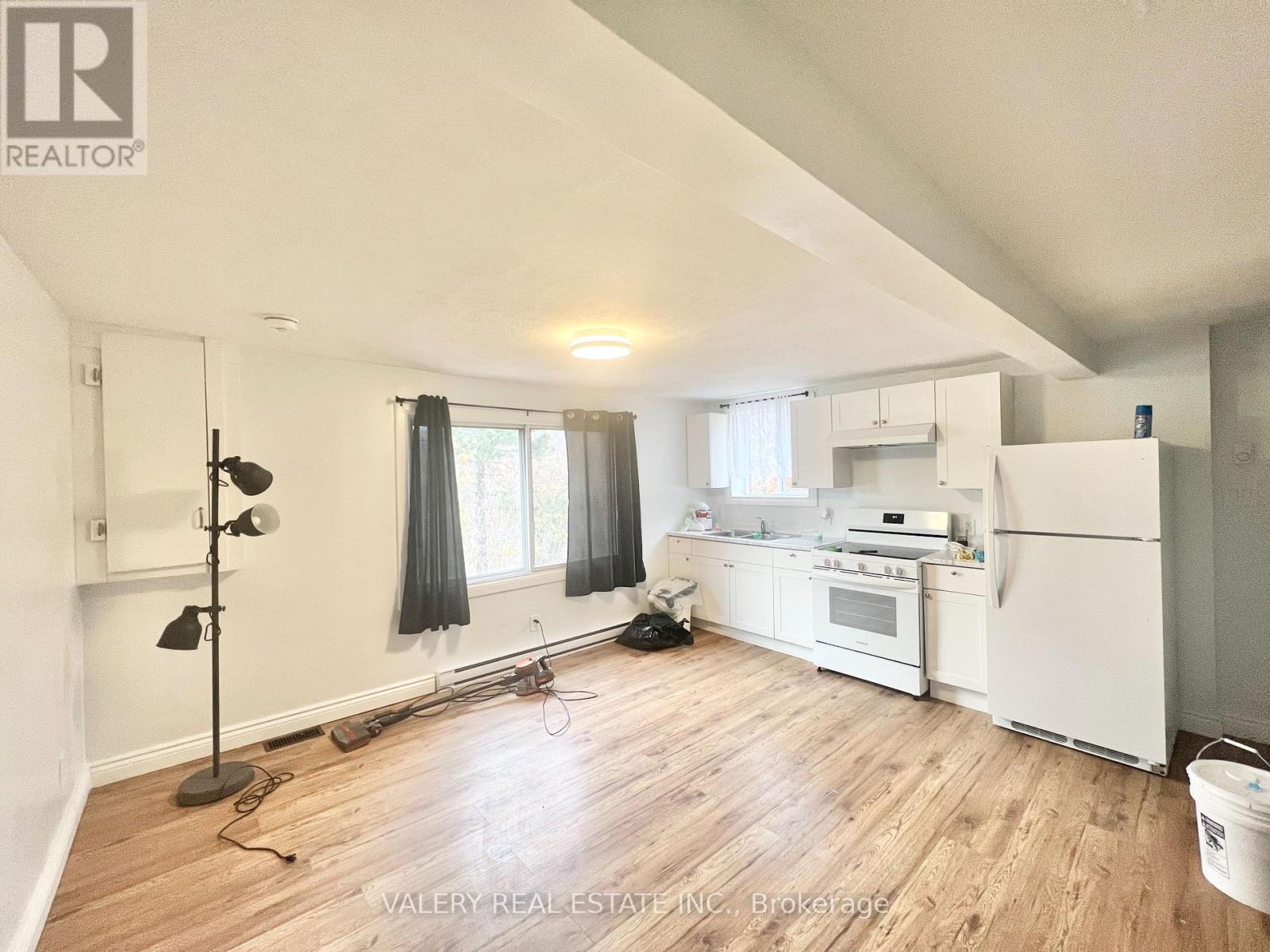 A kitchen with white appliances and wooden floors.