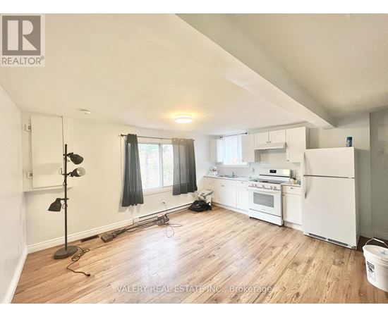 A kitchen with white appliances and wooden floors.