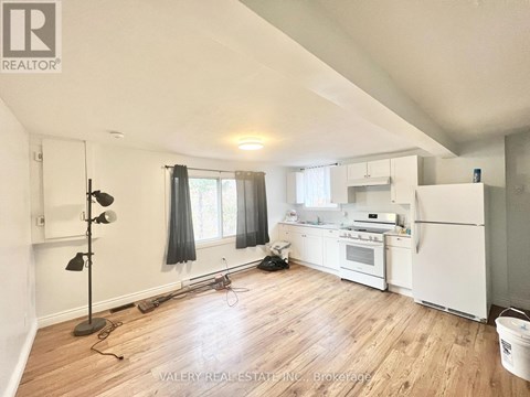 A kitchen with white appliances and wooden floors.