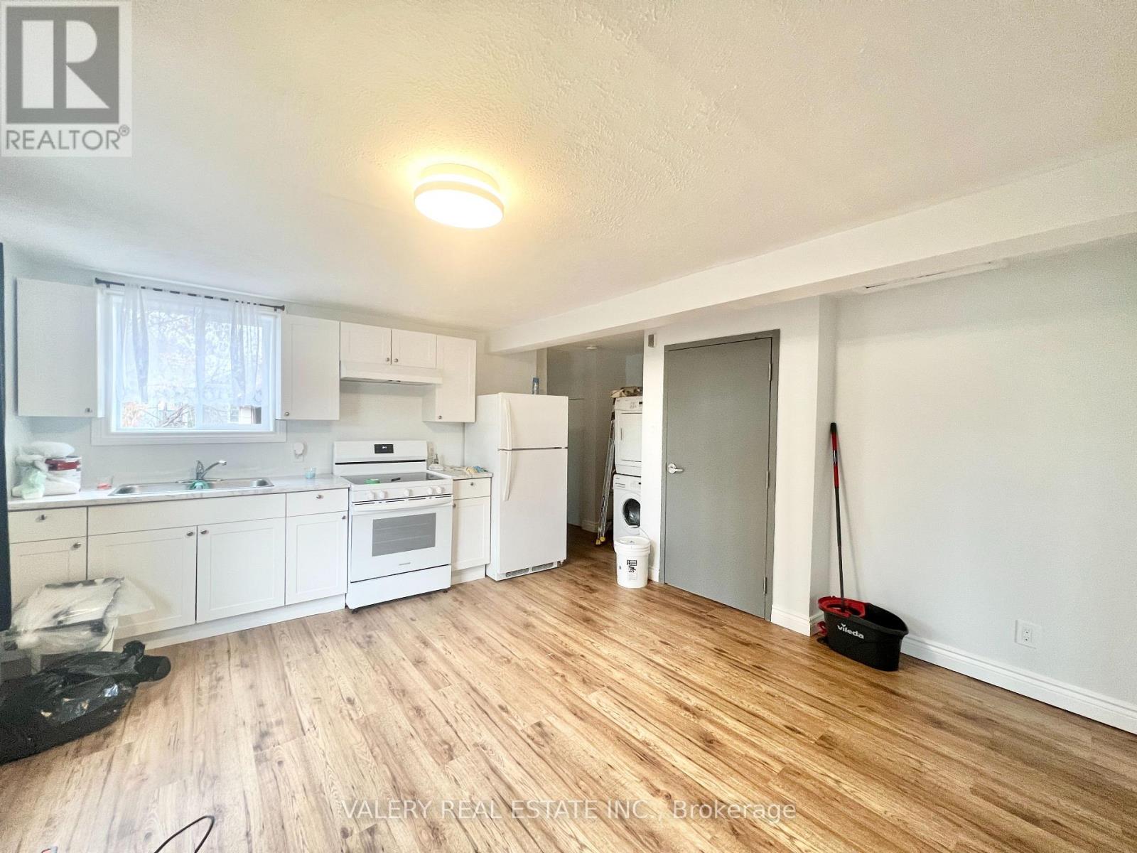 A kitchen with white appliances and wooden floors.