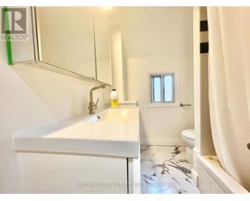 A white bathroom with a marble floor and a small window.