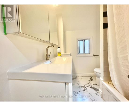 A white bathroom with a marble floor and a small window.