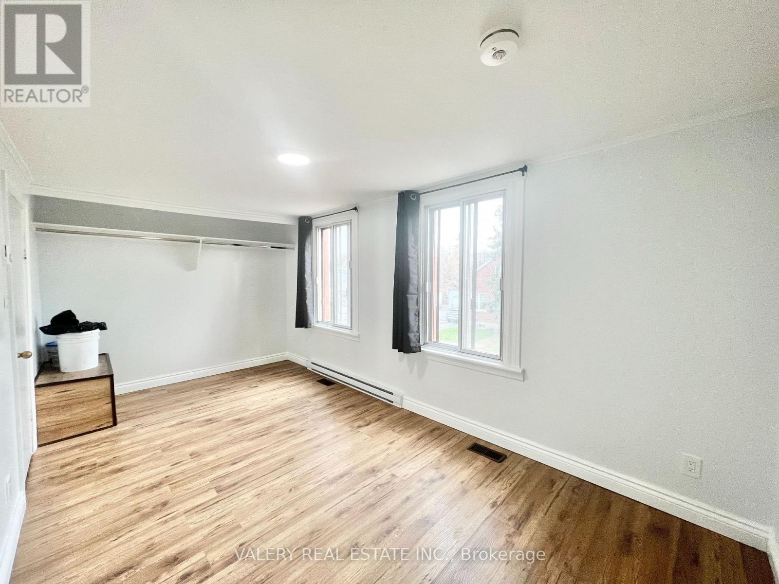 A room with wooden floors and white walls, with a window on the right side.
