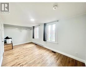 A room with wooden floors and white walls, with a window on the right side.