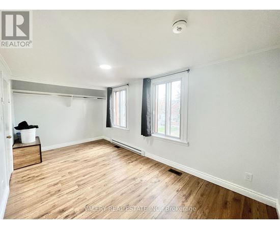 A room with wooden floors and white walls, with a window on the right side.