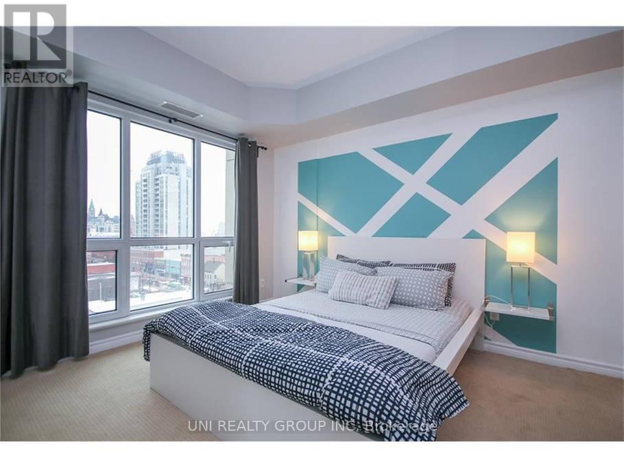 A bedroom with a large bed and a window overlooking a cityscape.