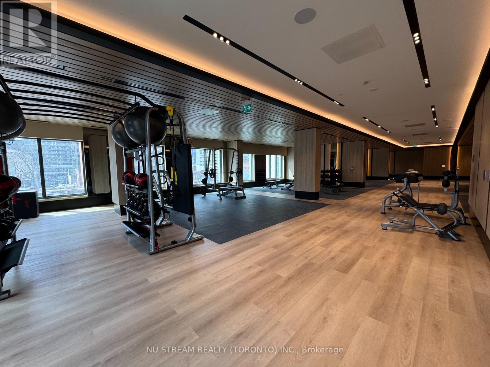 A gym with wooden floors and various exercise equipment.