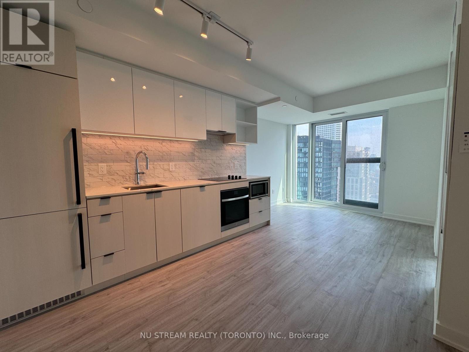 A modern kitchen with white cabinets and a marble backsplash.
