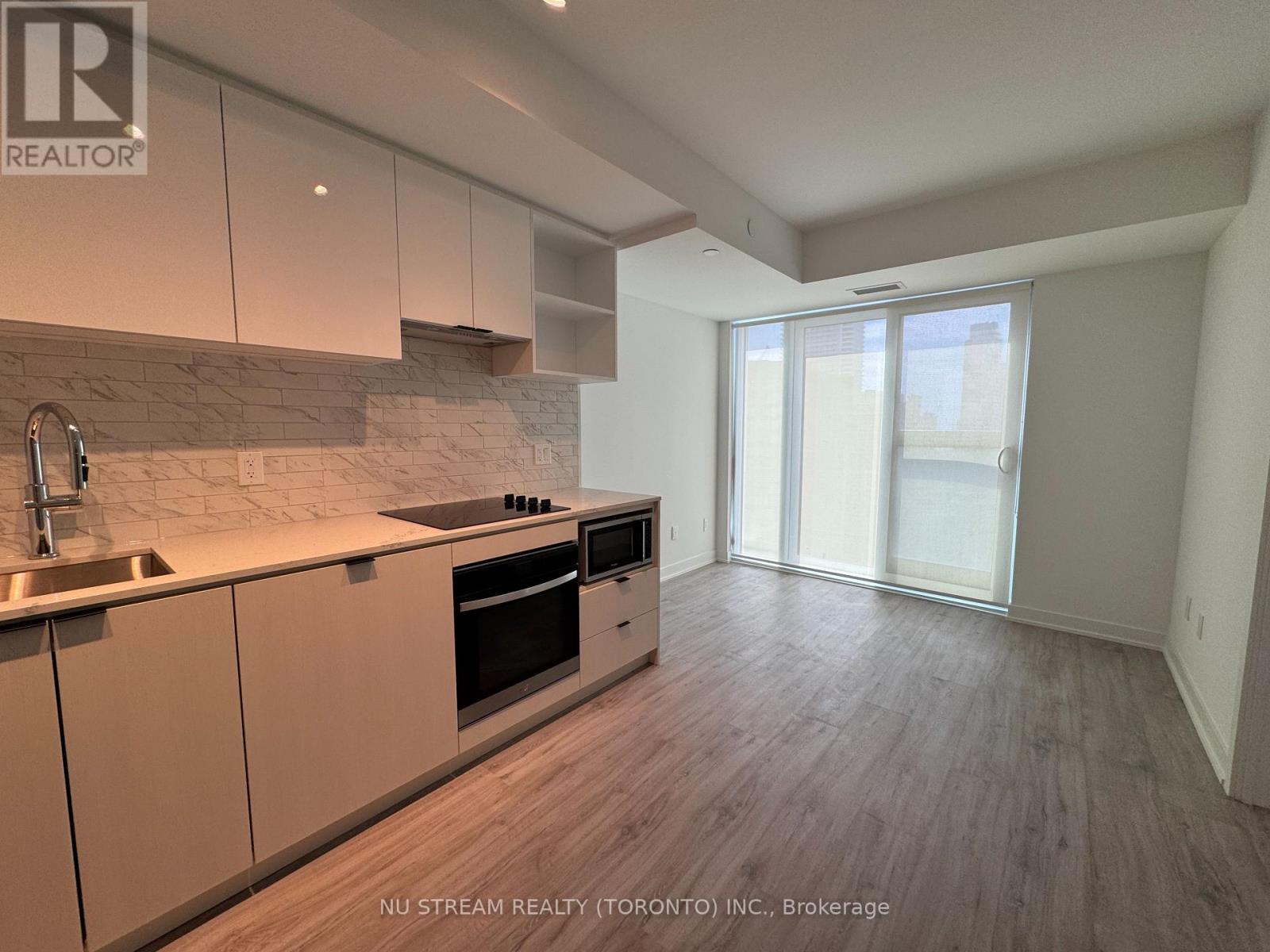 A modern kitchen with wooden floors and a marble backsplash.