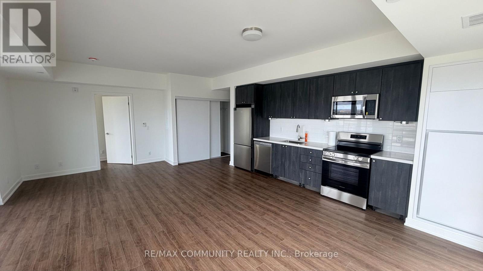 A spacious kitchen with dark wood floors and white walls.