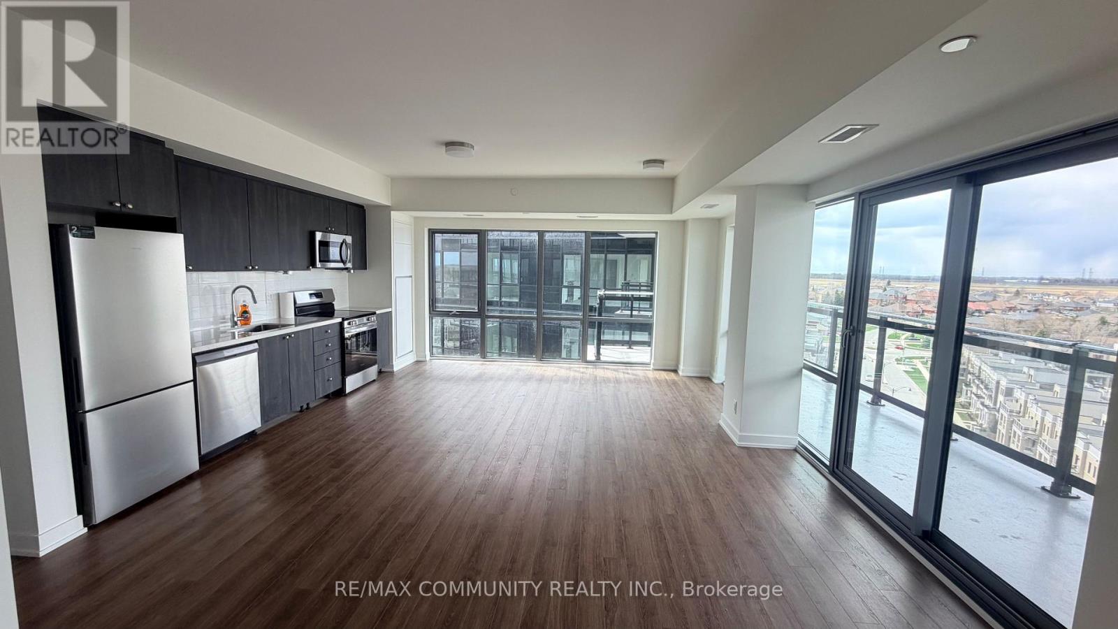 A spacious kitchen with dark wood floors and a view of the city.