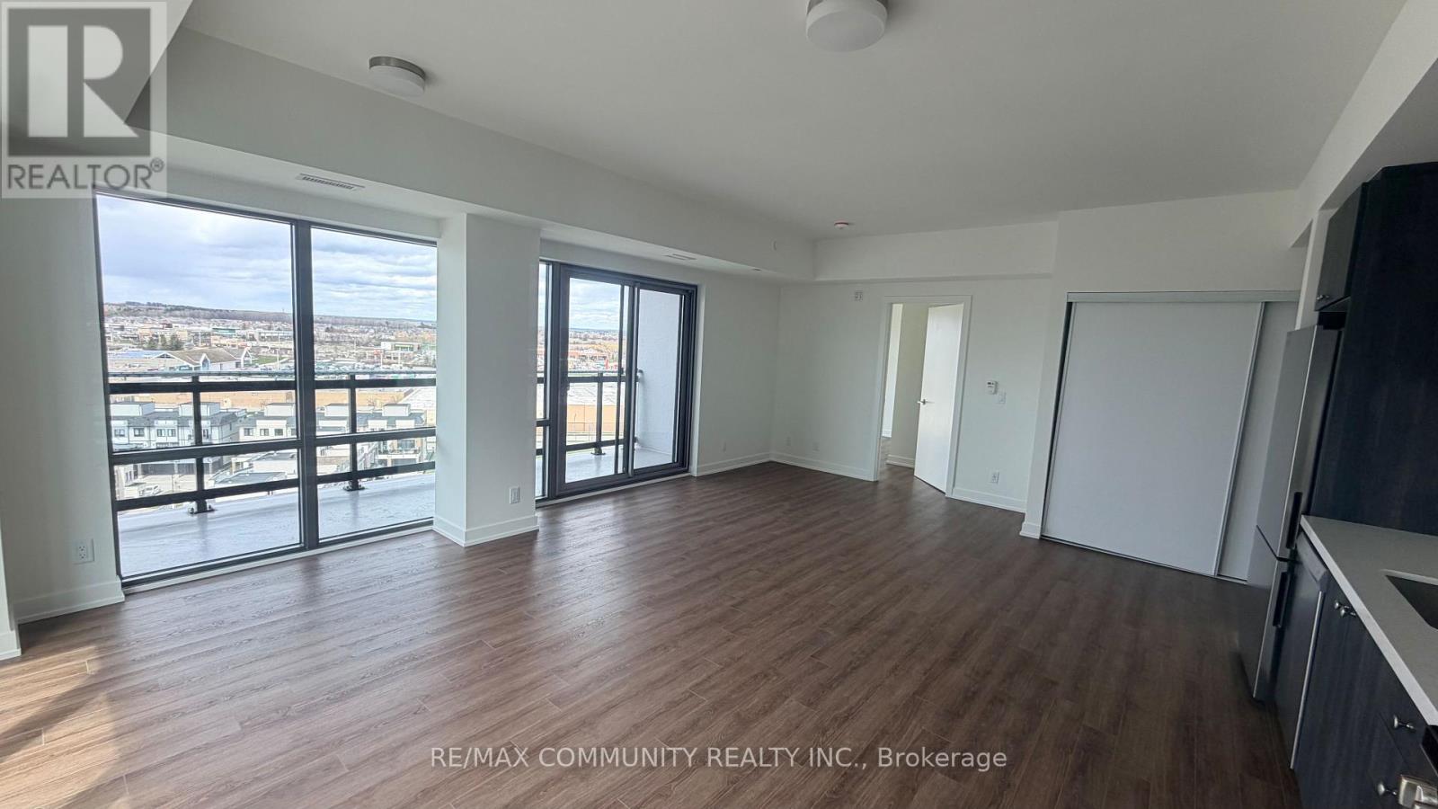 A spacious room with wooden floors and large windows overlooking a cityscape.