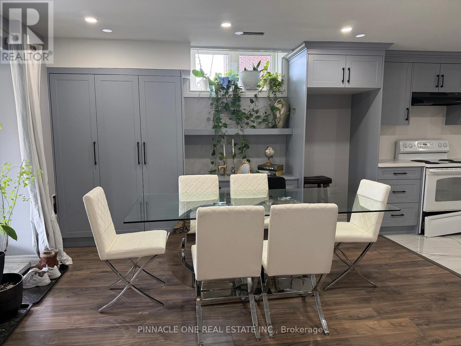A modern kitchen with a glass table and white chairs.