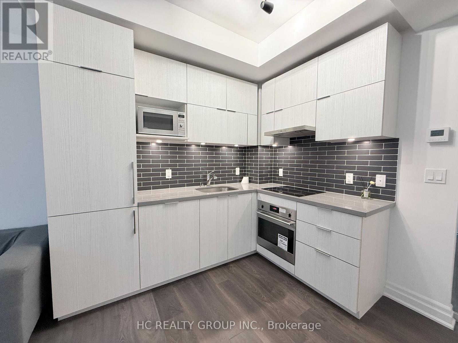 A kitchen with white cabinets and a brick backsplash.