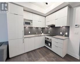 A kitchen with white cabinets and a brick backsplash.