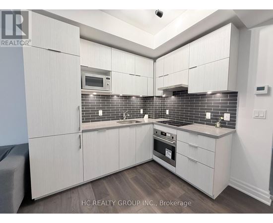 A kitchen with white cabinets and a brick backsplash.