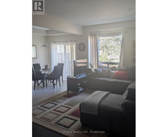 A living room with a grey couch and a dining table with chairs.