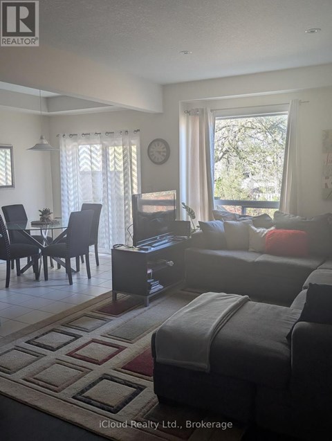 A living room with a grey couch and a dining table with chairs.