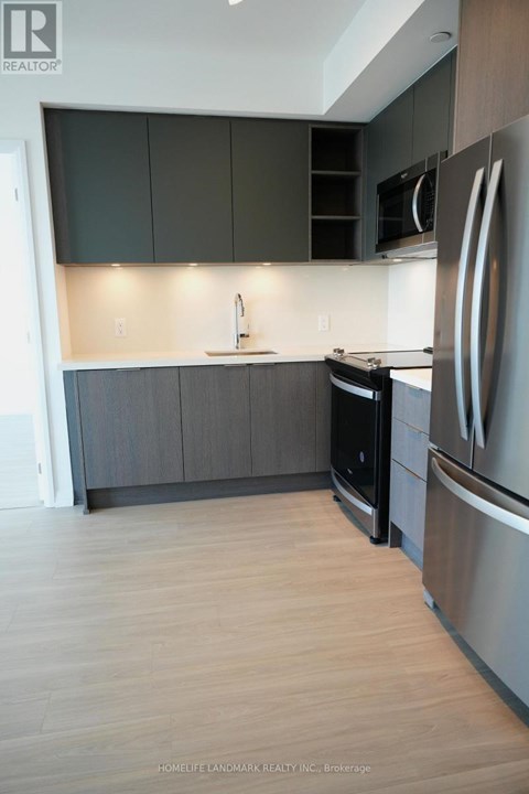 A modern kitchen with dark grey cabinets and stainless steel appliances.