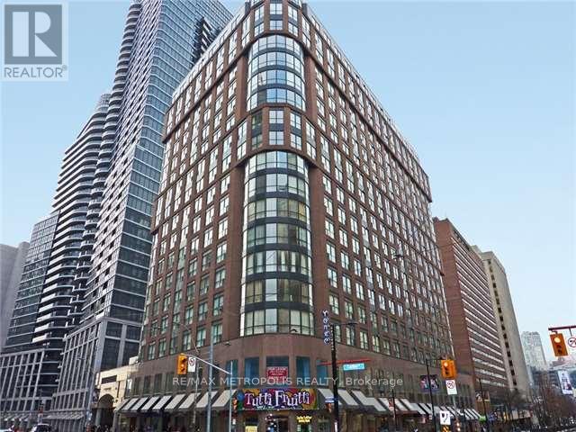 A tall building with a curved glass facade stands next to a shorter building with a brick facade.