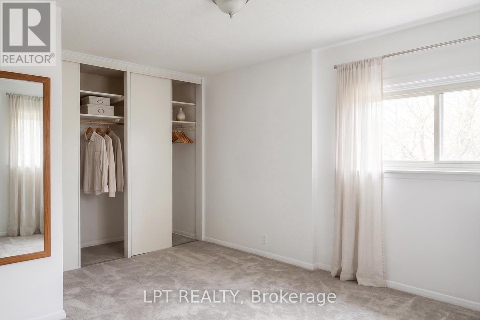 A bedroom with a walk-in closet and a window with curtains.